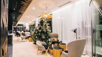 A modern interior with a Christmas tree, seating area, and a glass partition.