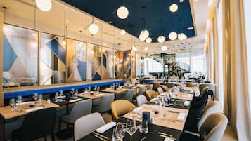 Un restaurante moderno con varias mesas, iluminación colgante y vistas del espacio interior.