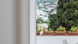 Ein Balkon mit Blick auf eine Stadt, einem weißen Stuhl und Kübelpflanzen.