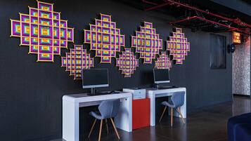 Een moderne kantoorruimte met twee bureaus, stoelen en een decoratieve wanddecoratie met geometrische vormen.