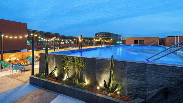 A swimming pool with a modern design, surrounded by a patio area with chairs and plants.