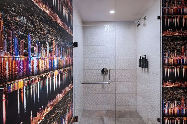 Un baño moderno con cabina de ducha de vidrio, un perchero y un mural con vistas a la ciudad en las paredes.
