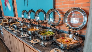 A buffet setup with multiple food stations, including salads, desserts, and a variety of dishes in stainless steel serving dishes.
