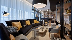 Una sala de estar moderna con un sofá seccional, sillones, una mesita de centro y una estantería.