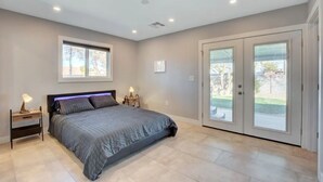 A bedroom with a bed, nightstands, a window, and a sliding glass door to a patio.