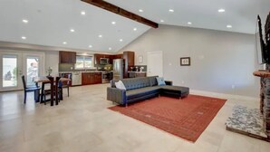 A spacious living area with a dining table, sofa, and kitchen in the background.