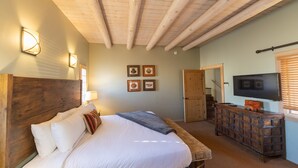 A bedroom with a wooden headboard, a bed with white linens, a bedside lamp, a wooden dresser, a flat-screen TV, and a framed picture on the wall. - Zona Rosa 71, San Rafael (Santa Fe)