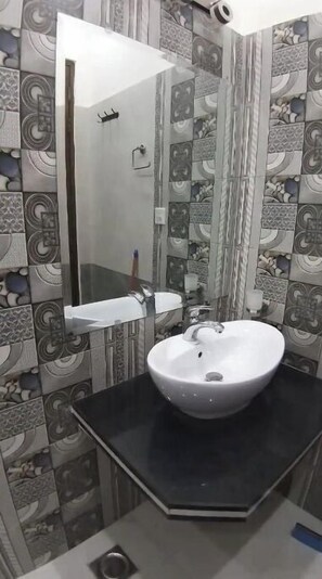 A bathroom with a white sink, black countertop, and patterned tile walls.