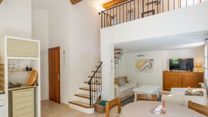 A spacious living area with a staircase, a dining table, and a television.