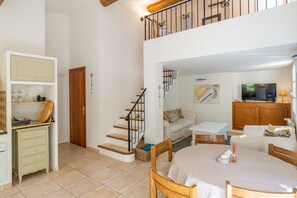 A spacious living area with a staircase, a dining table, and a television.