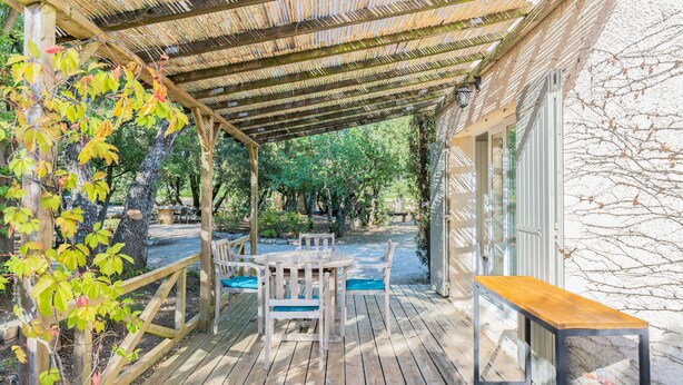 A wooden deck with a table and chairs, a bench, and a pergola.