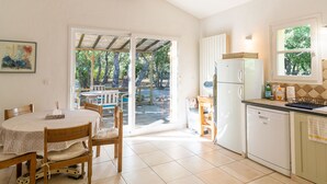 A kitchen with a dining area, a refrigerator, a dishwasher, and a window overlooking a garden.
