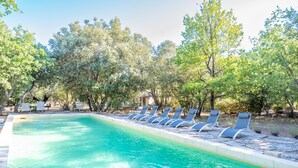 A swimming pool with lounge chairs and trees in the background.