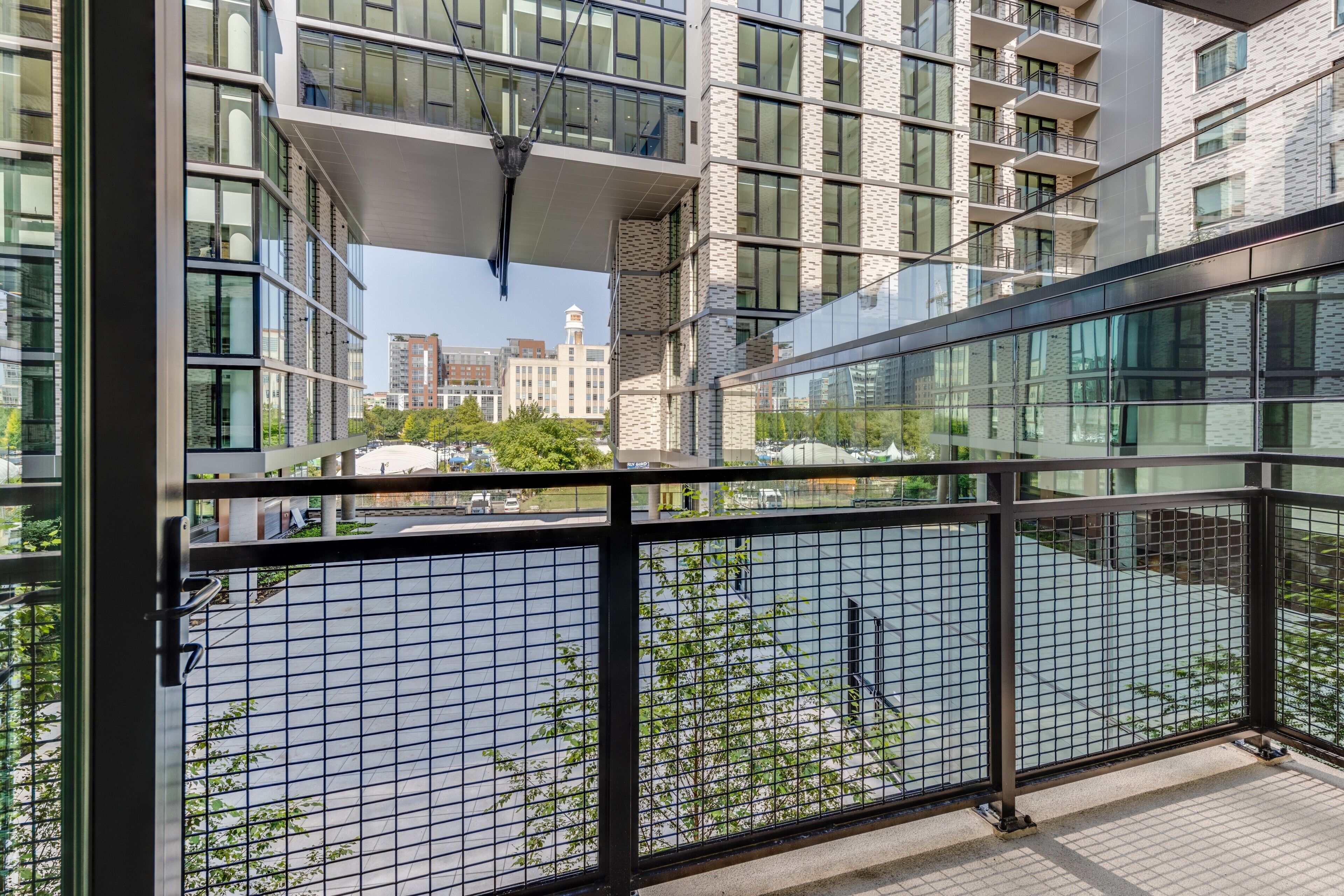 A modern building with multiple floors, large windows, and a balcony with a metal railing.
