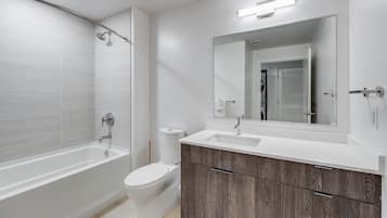 A modern bathroom with a bathtub, toilet, and vanity with a mirror.