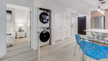 A modern kitchen with a glass dining table, blue chairs, and a built-in oven.
