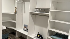 Un dressing accessible sans porte, doté d’étagères ouvertes, d’une tringle et d’un tapis à motifs.