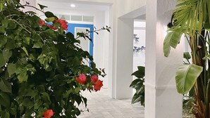An indoor corridor with white walls, a tiled floor, and a blue door in the background.
