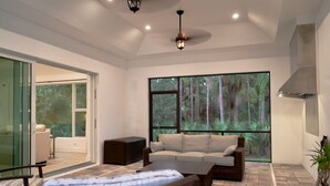 A modern living room with a large window, a sofa, a dining table, and a bed.