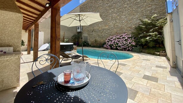 Un patio con piscina, muro de piedra y mobiliario para exterior.