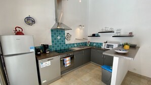 Una cocina compacta equipada con refrigerador, estufa, microondas y pileta.