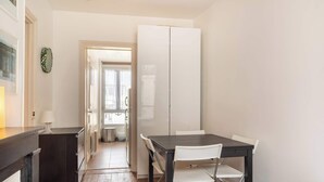 Una cocina compacta con encimera oscura, armarios blancos y un comedor con mesa y sillas.