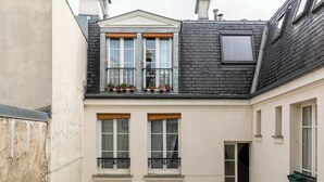 Un edificio con balcón, varias ventanas y chimenea.