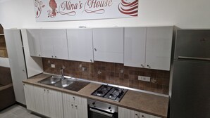 A kitchen with white cabinets, a gas stove, a sink, and a refrigerator. - Nina's house 2 300 meters from the sea (Santa Caterina Dello Ionio Marina)