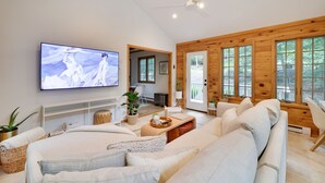 Un salon moderne doté d’un grand téléviseur à écran plat, d’un canapé, d’une table basse et de murs en bois.