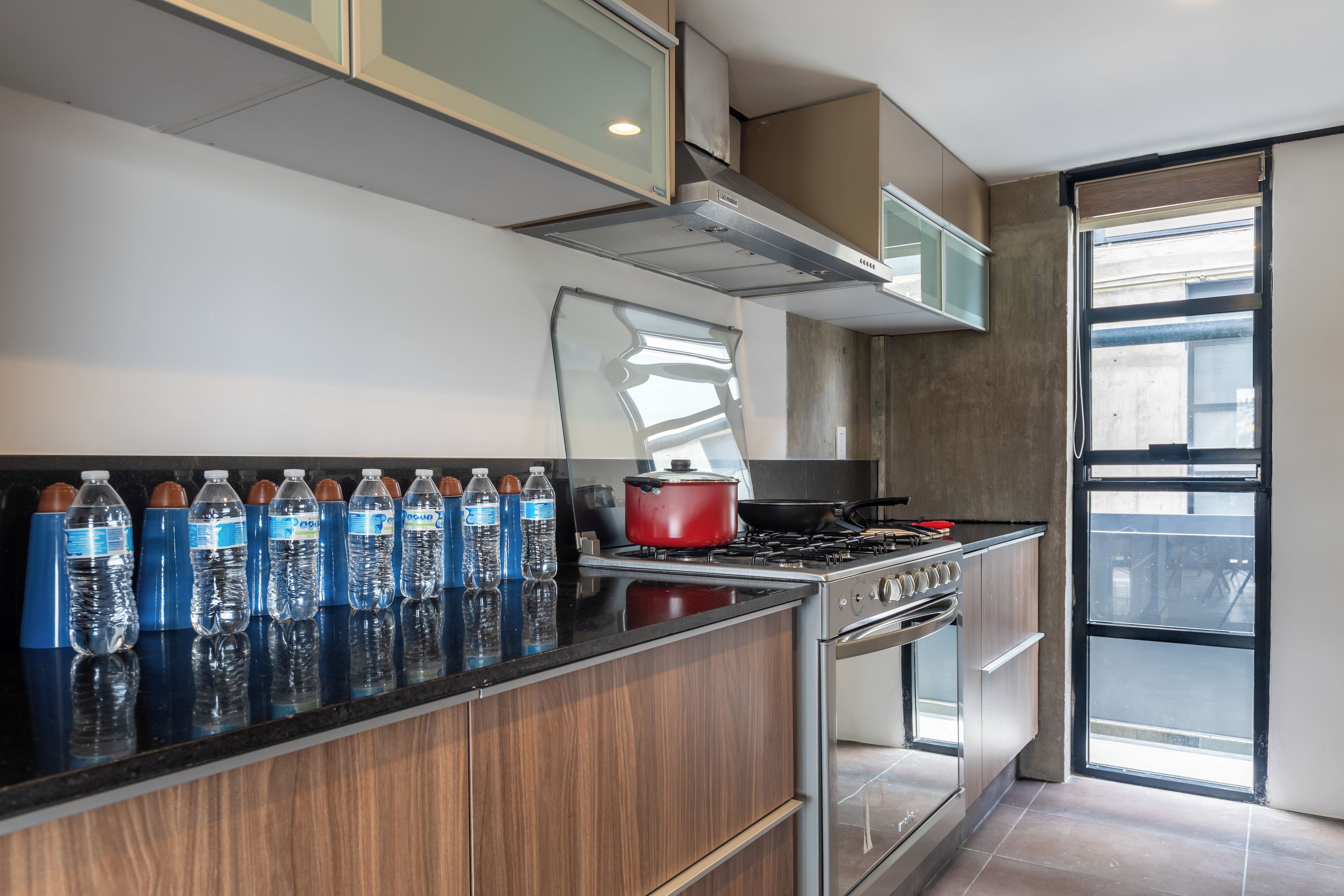 A modern kitchen with a gas stove, oven, and a row of water bottles on the counter.