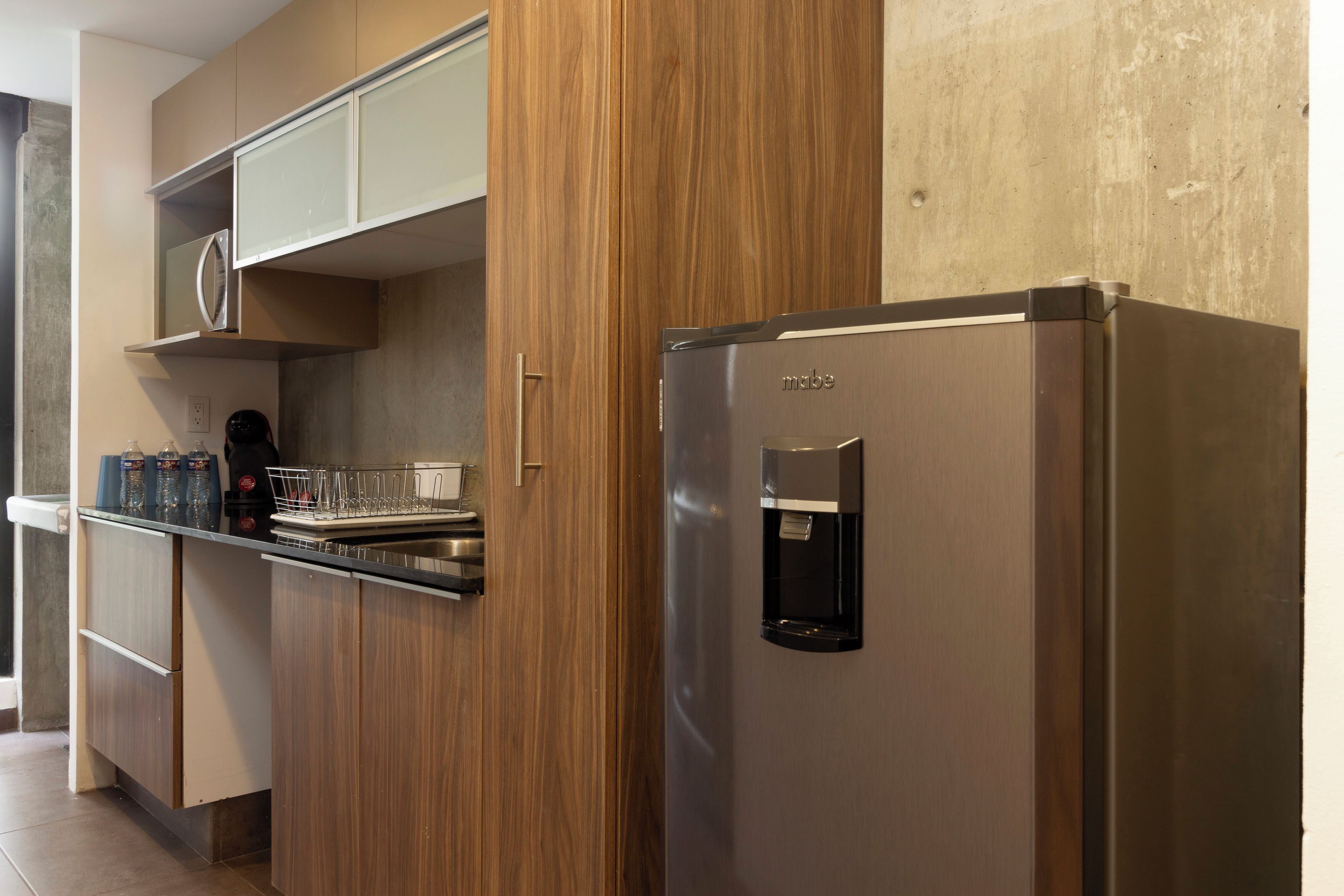 A modern kitchen with wooden cabinets, a stainless steel refrigerator, and a water dispenser.