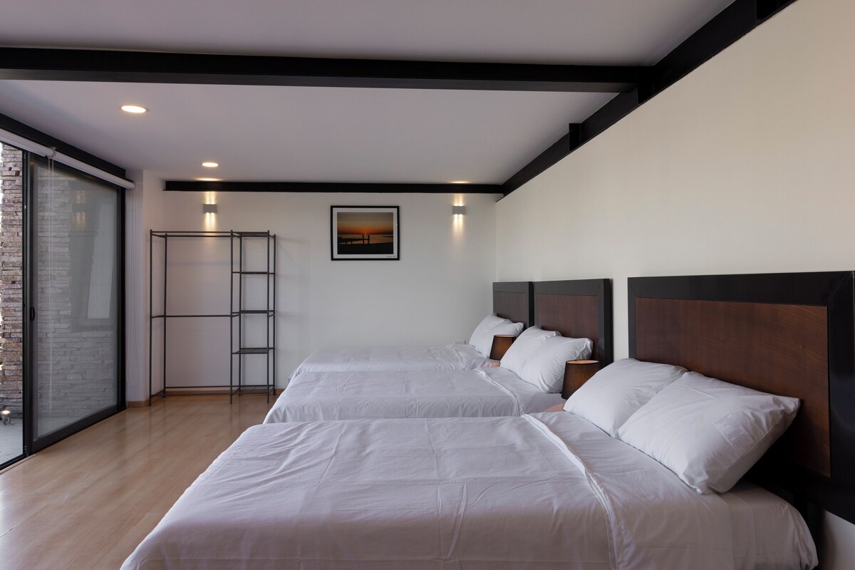 Ett hotellrum med två sängar, ett stort fönster och utsikt över solnedgången.
