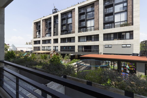 A multi-story building with balconies, a rooftop garden, and a playground area.