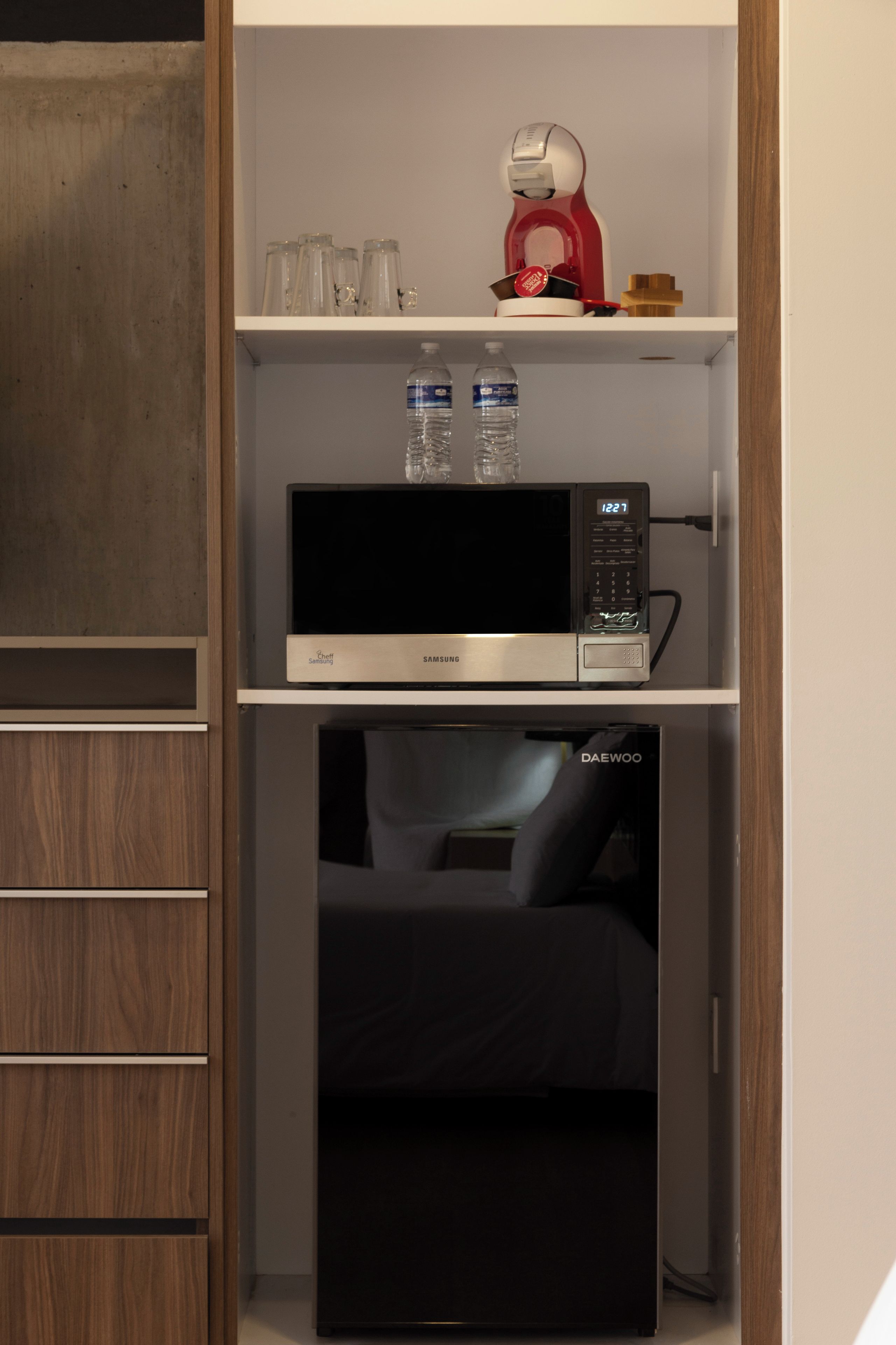 A compact kitchenette with a microwave, a refrigerator, and a small cabinet.