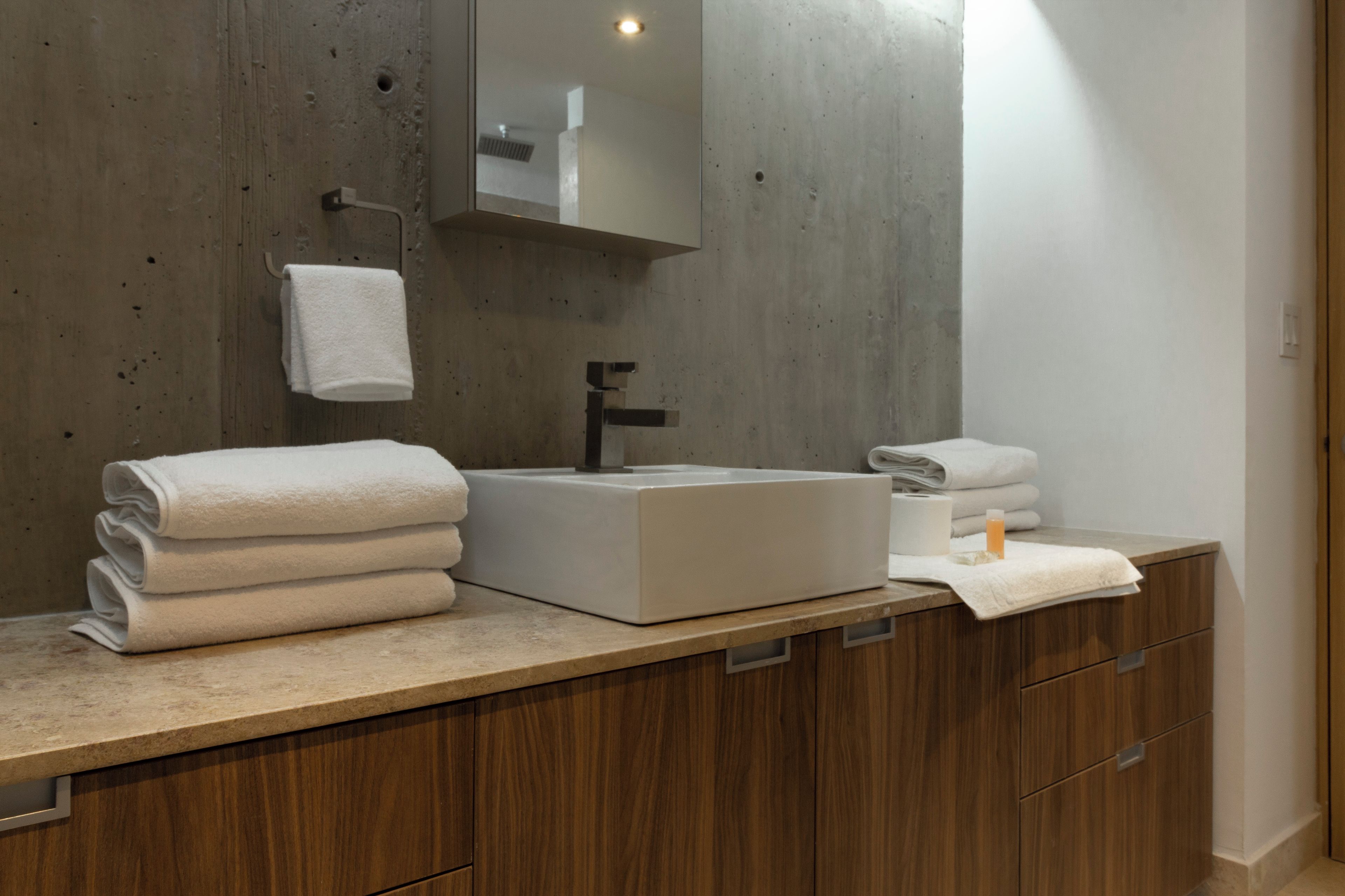 Un baño moderno con un lavamanos grande, armarios de madera y un espejo sobre el lavamanos.