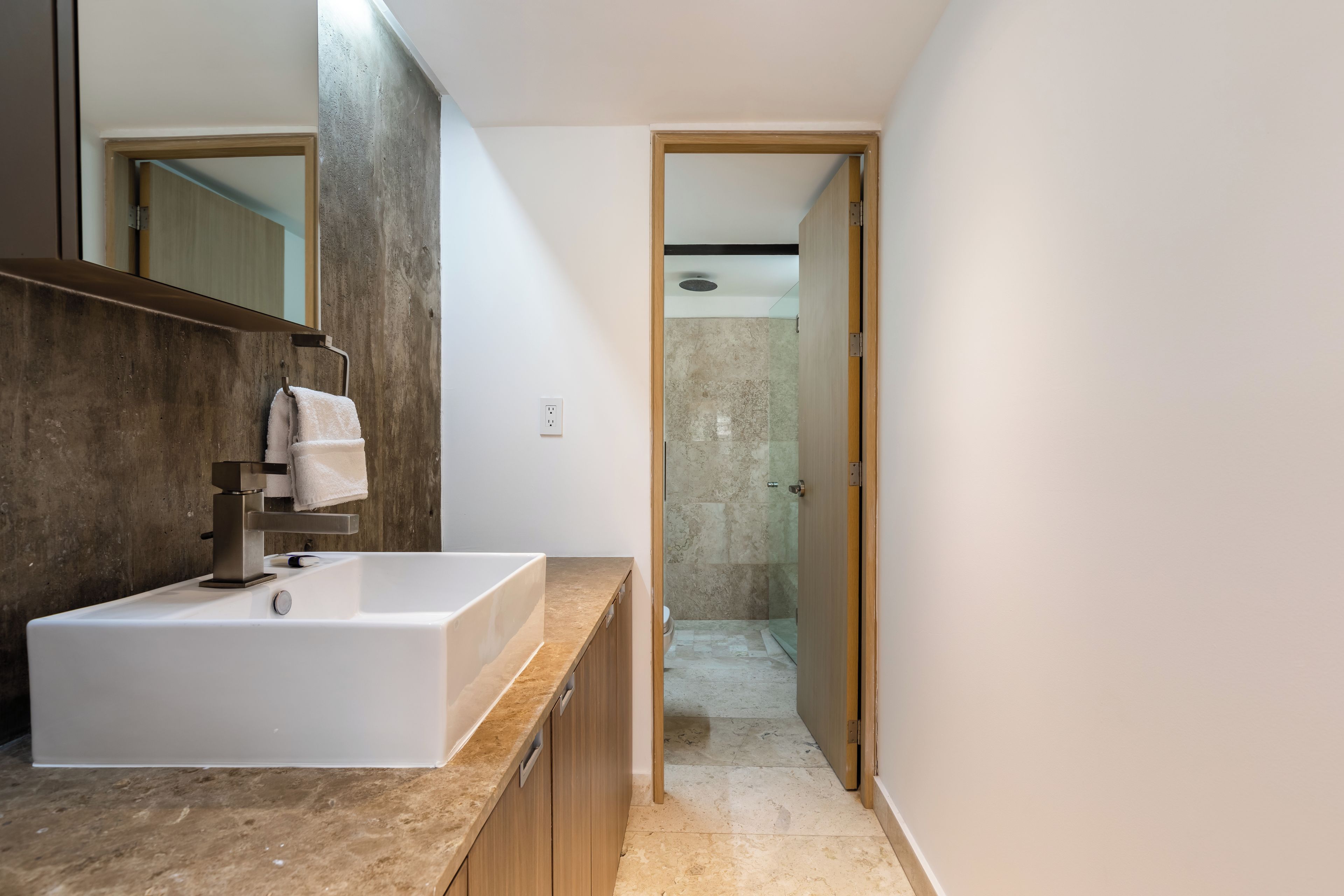 A modern bathroom with a large sink, a mirror, and a shower area.
