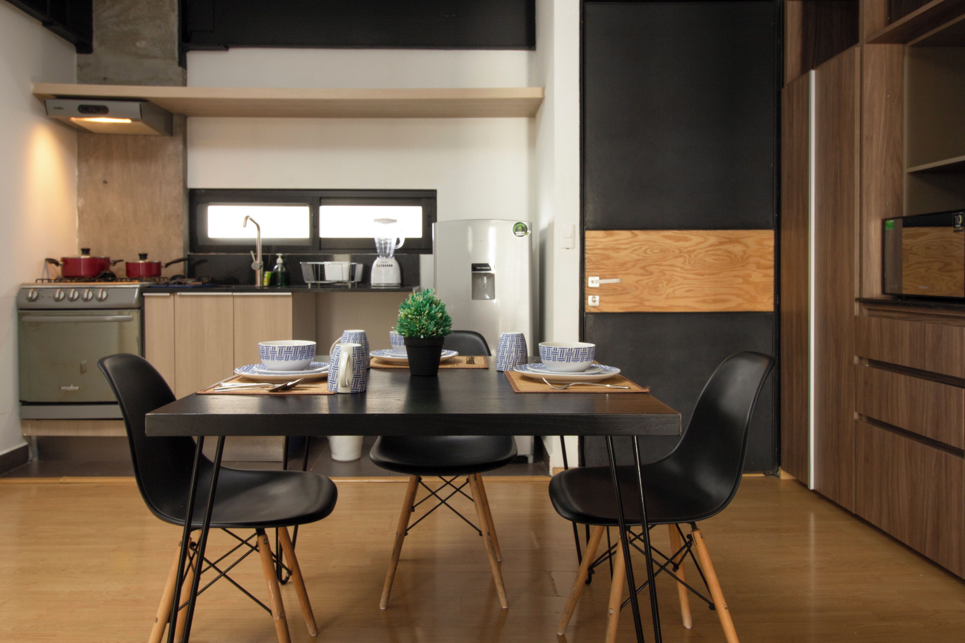 A modern kitchen with a dining table set for four, a stove, and a refrigerator.
