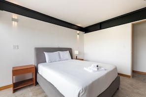 Een moderne hotelkamer met een groot bed, een nachtkastje, een lamp en een deur.