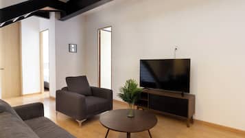 Una sala de estar moderna con un sofá, una mesa de centro y un televisor sobre un mueble.