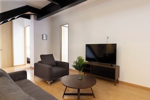 A modern living room with a sofa, a coffee table, and a TV on a stand.