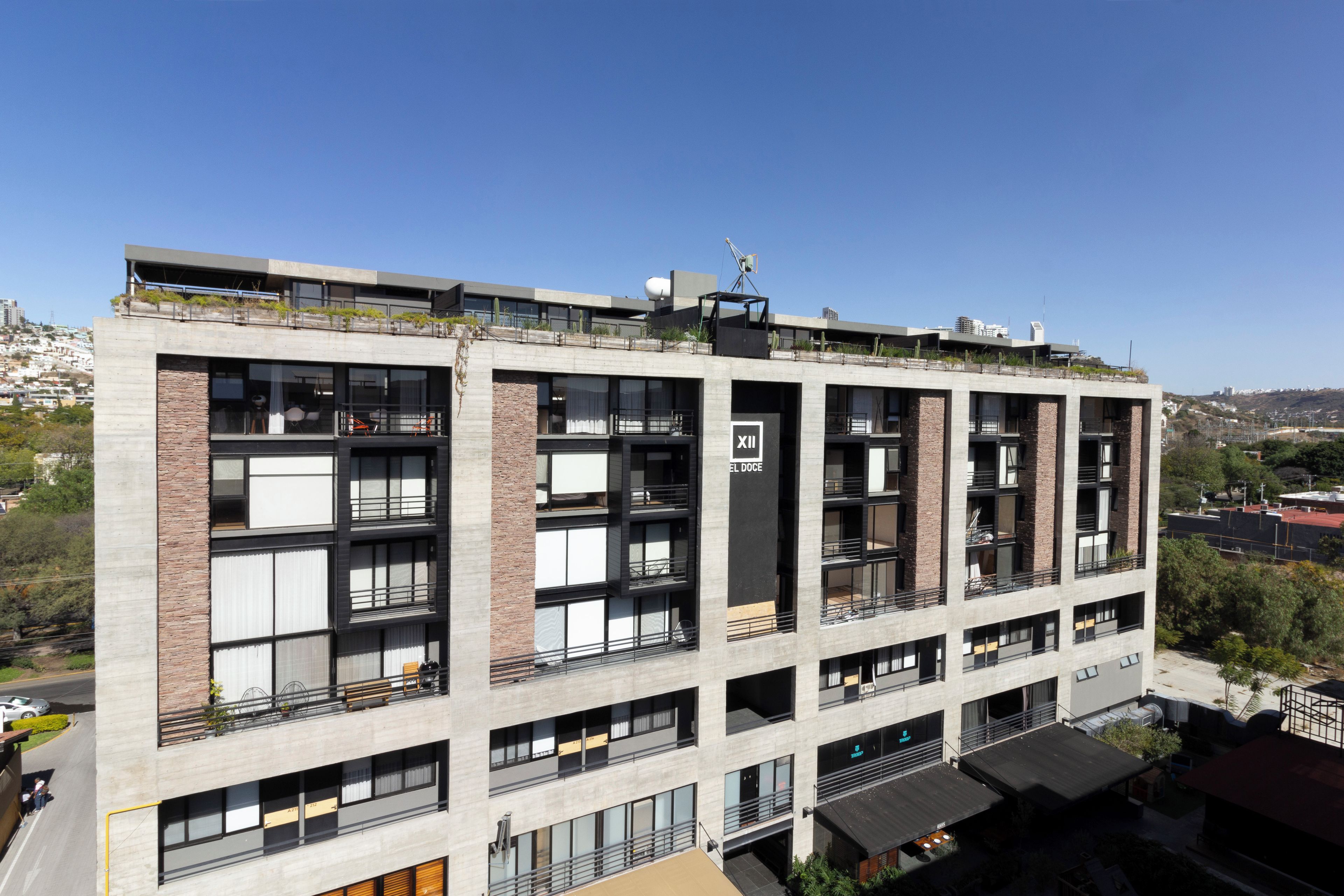 A multi-story hotel with balconies, large windows, and a rooftop terrace.