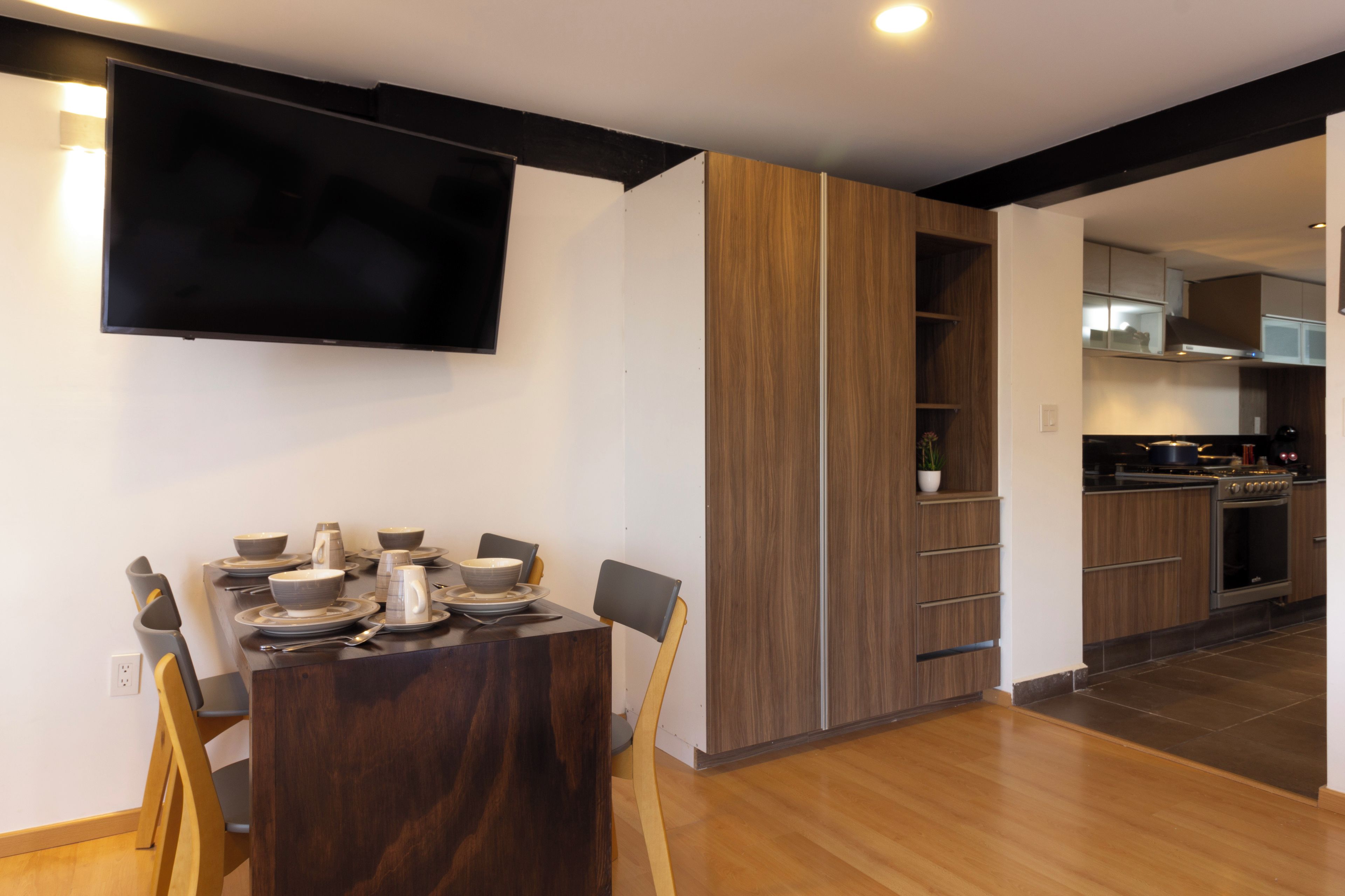 Una cocina moderna con armarios de madera, horno empotrado y un comedor con mesa y sillas de madera oscura.