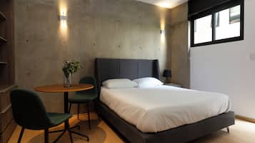 Un dormitorio moderno con cama, mesita de noche, silla y una pequeña mesa con un florero.
