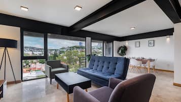 A modern living room with a sofa, chairs, a coffee table, and a dining area with a table and chairs.