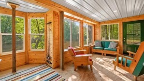 A cabin with large windows, a wooden interior, a green sofa, and a colorful rug.