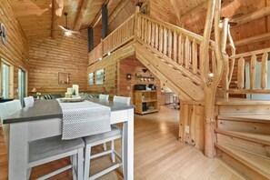 Ein Holzblockbau-Innenraum mit Essbereich, Küche und einer Treppe zu einer oberen Ebene.