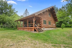 Eine Blockhütte mit Veranda, einer kleinen Terrasse und einem Fenster.