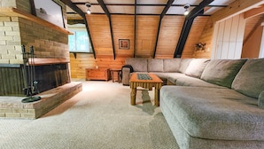 A cozy living room with a fireplace, a sofa, and a wooden ceiling. - A-Frame | Hot Tub, Fireplace, River, Kayaks &Tubes (Sears)