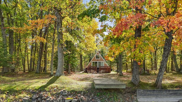 A cabin surrounded by a forest with a small stream and a wooden dock. - A-Frame | Hot Tub, Fireplace, River, Kayaks &Tubes (Sears)