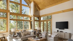 A spacious living room with large windows, a flat-screen TV, and comfortable seating. - Outpost: Granite Ridge Chateau (Teton Village)